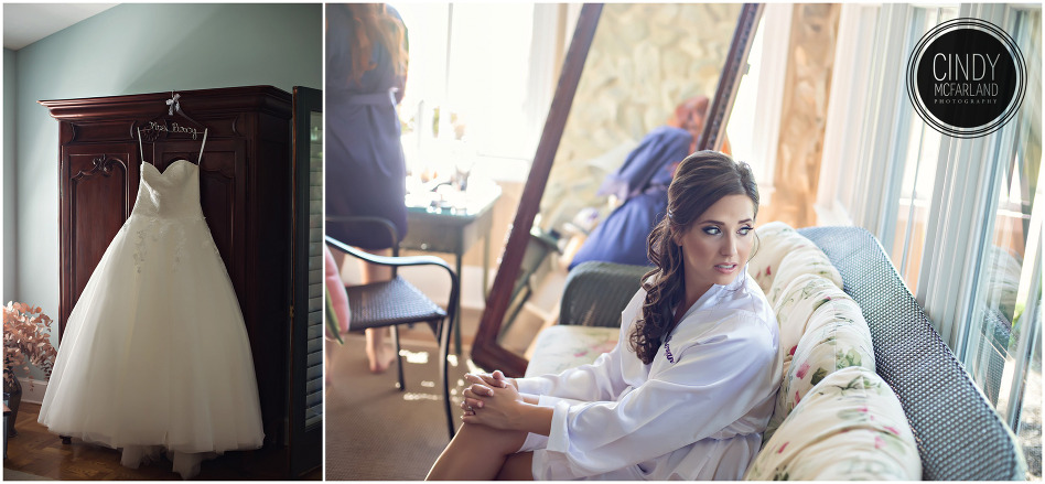 Gorgeous ballgown style wedding dress hanging on armoire while bride looks out window