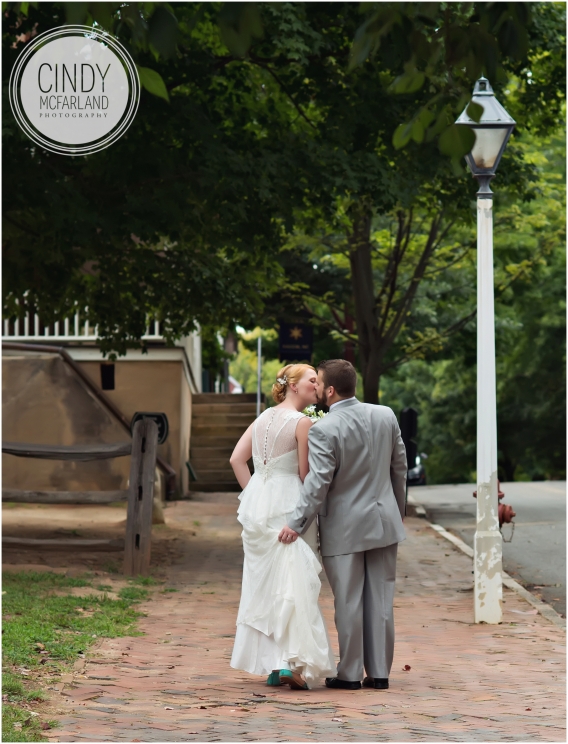 Photo from behind of bride and groom walking and groom is holding bride