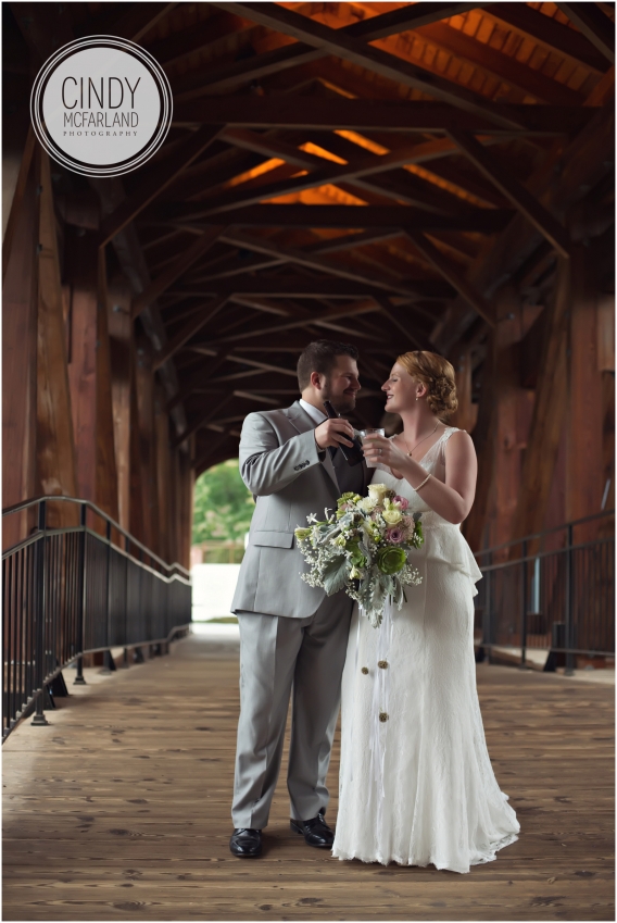 Bride and groom toast on covered bridge at Old Salem